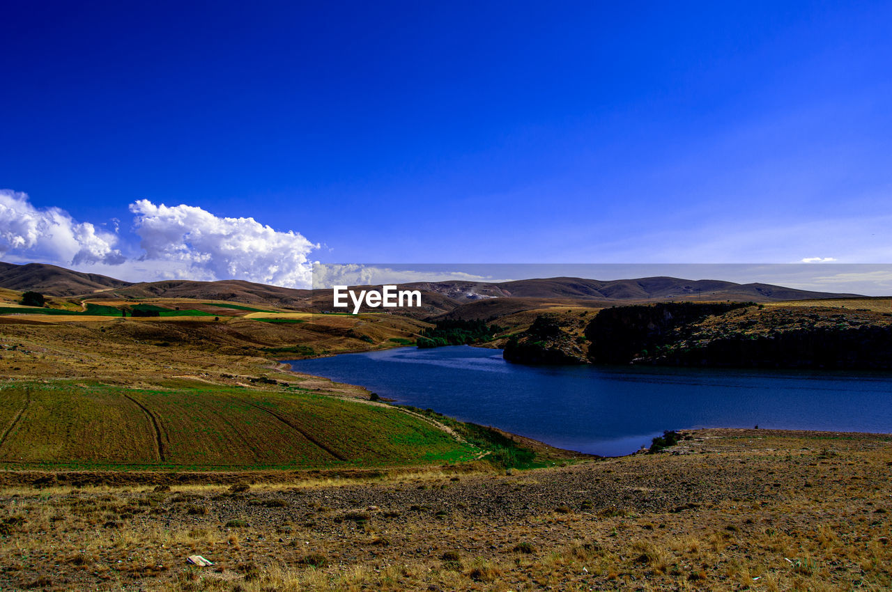 Scenic view of lake and mountains against blue sky