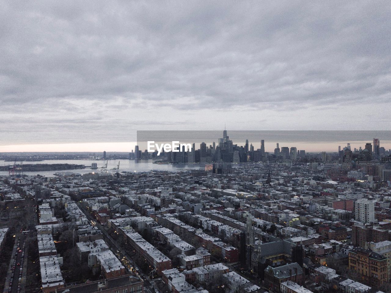 Aerial view of cityscape against cloudy sky