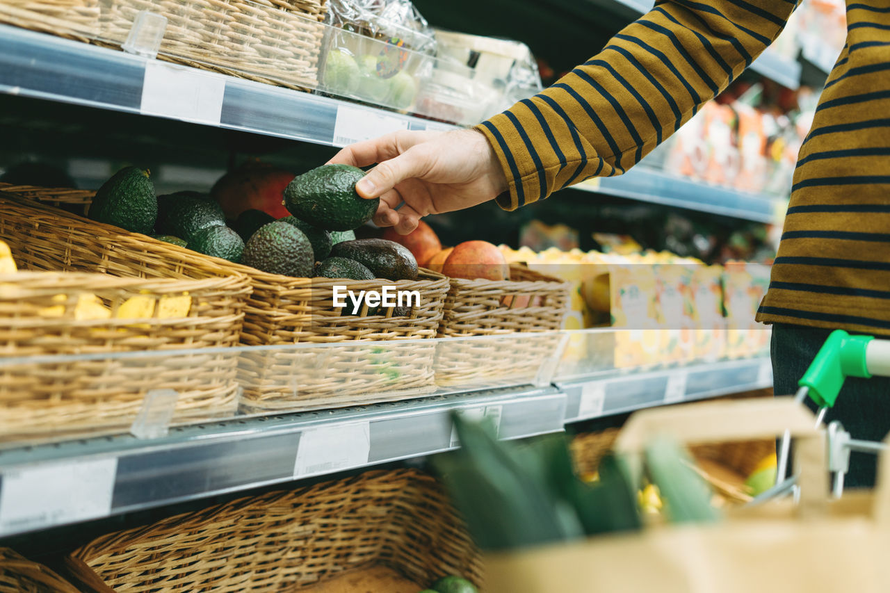 MIDSECTION OF MAN EATING FOOD AT STORE