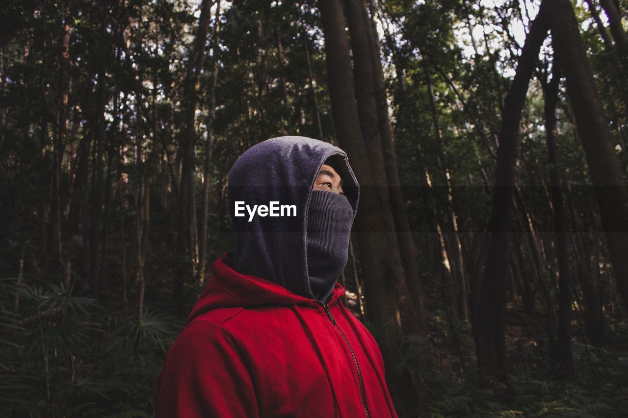 Man with covered face looking away in forest