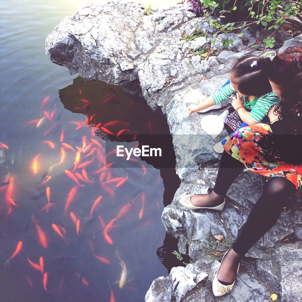 Mother and daughter watching koi carps