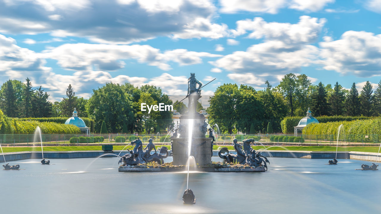 STATUE BY FOUNTAIN AGAINST TREES AND SKY