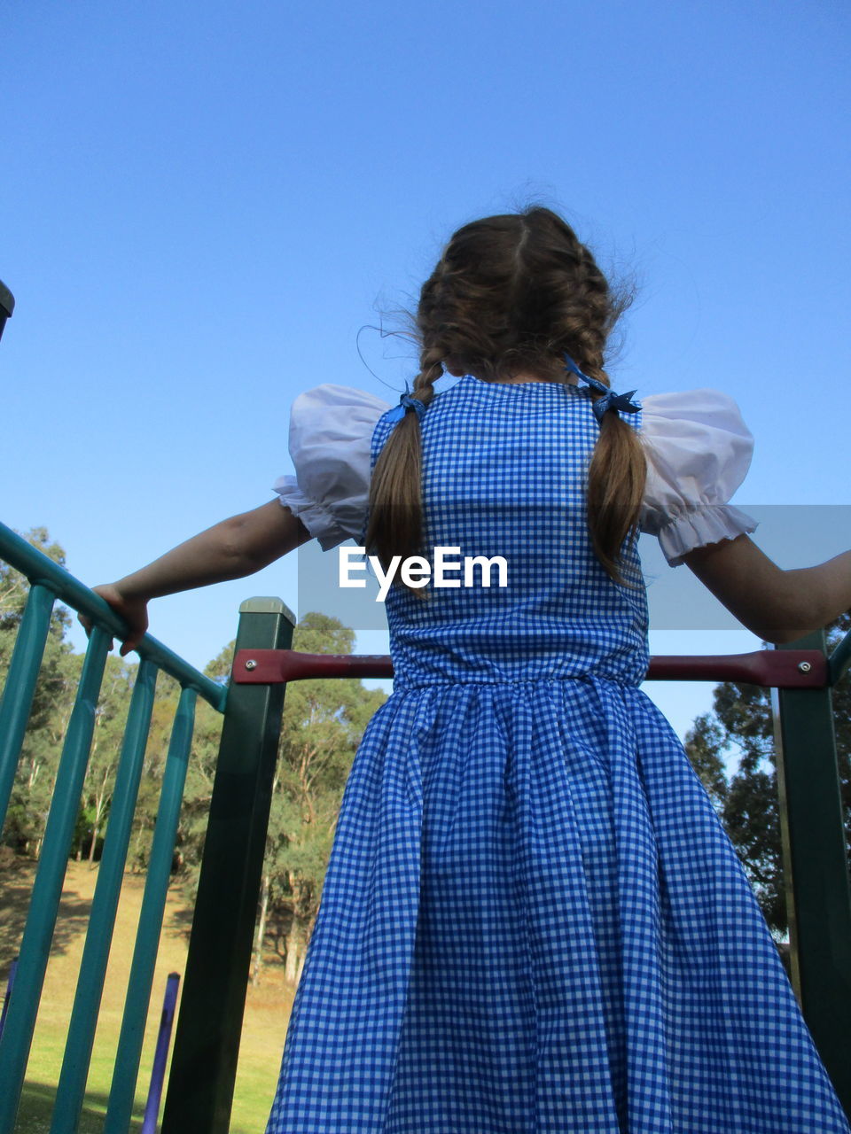 Rear view of girl standing against clear blue sky