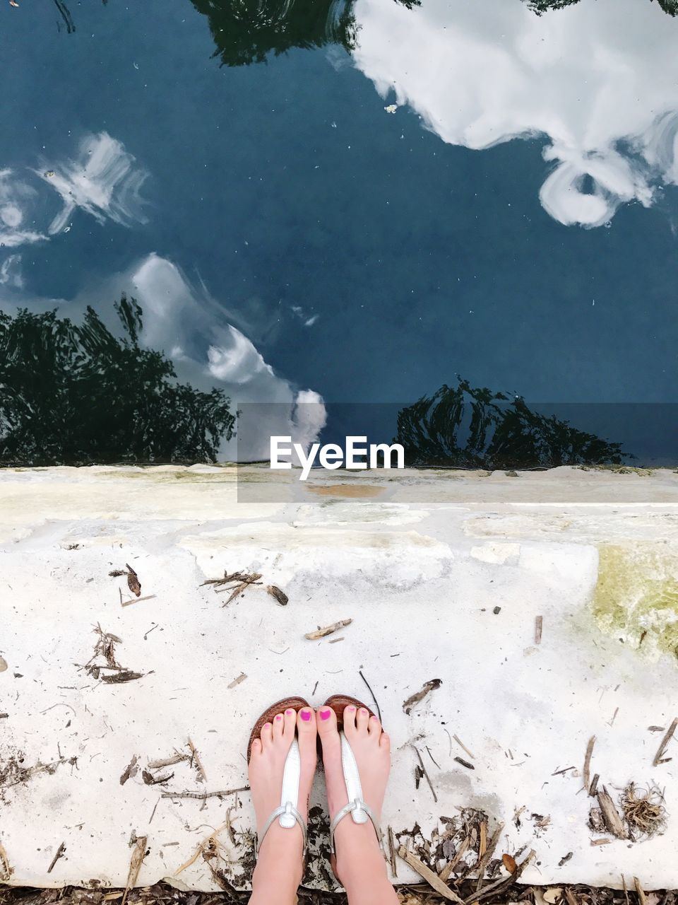 Directly above shot of woman standing by lake reflecting sky