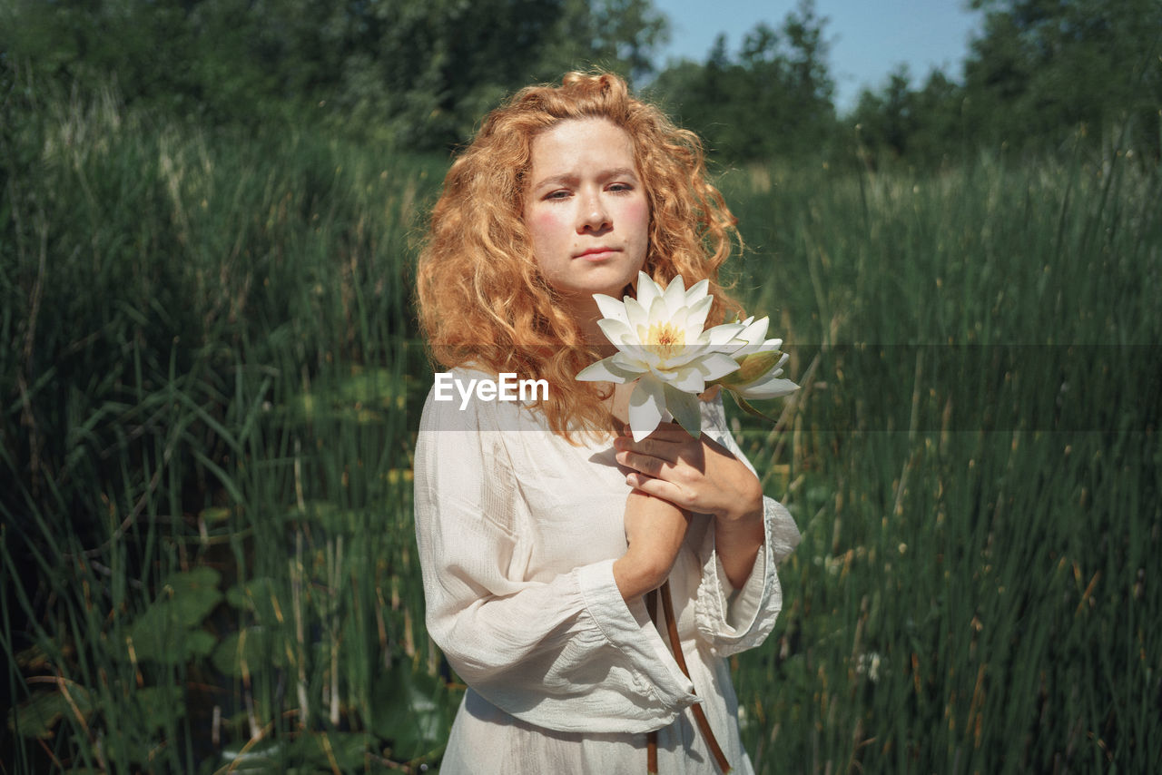 Young woman with flower petals on the lake 