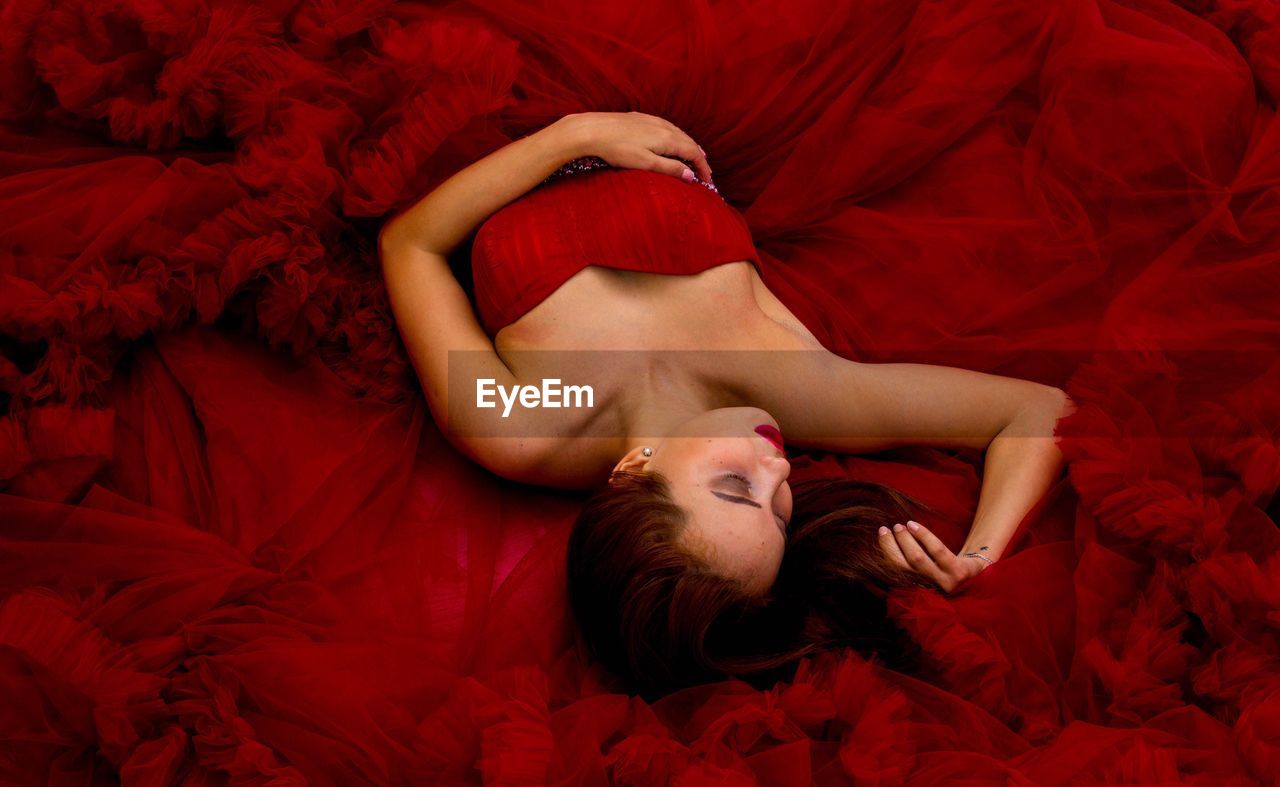High angle view of young fashion model lying in red dress