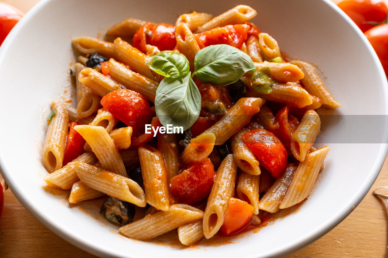 Italian pasta with tomato and olives. high angle view of fruits in container on table