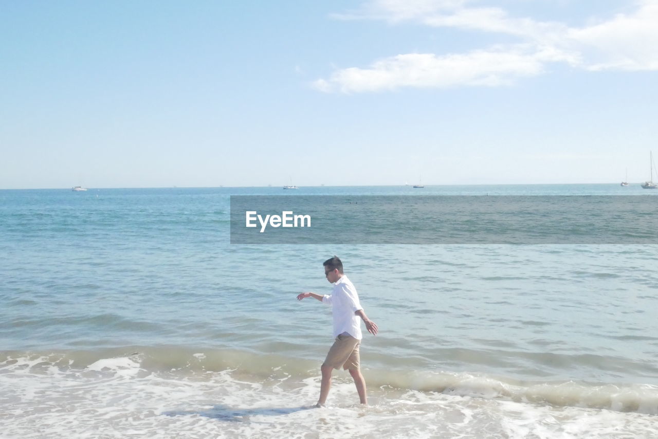 Full length of man standing on beach against sky