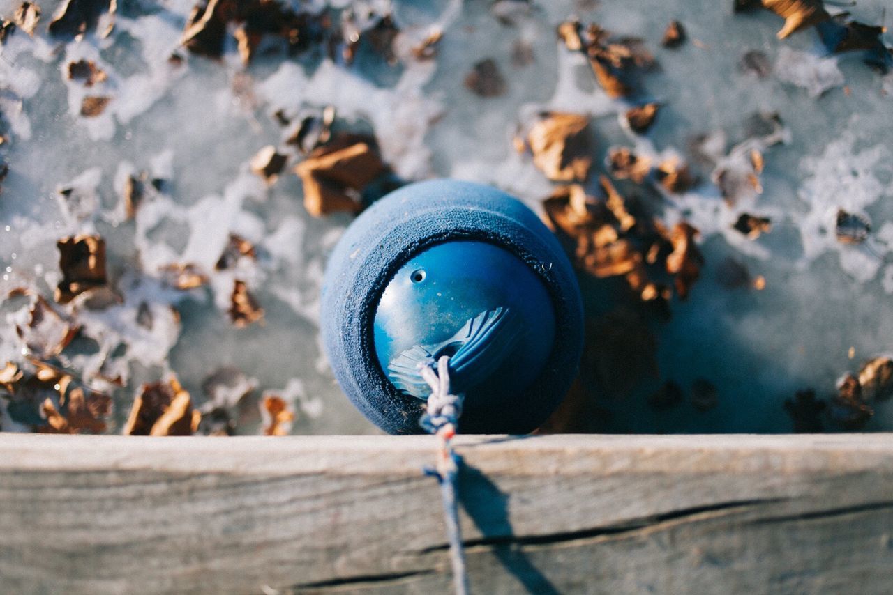 Directly above shot of blue buoy hanging from pier at beach