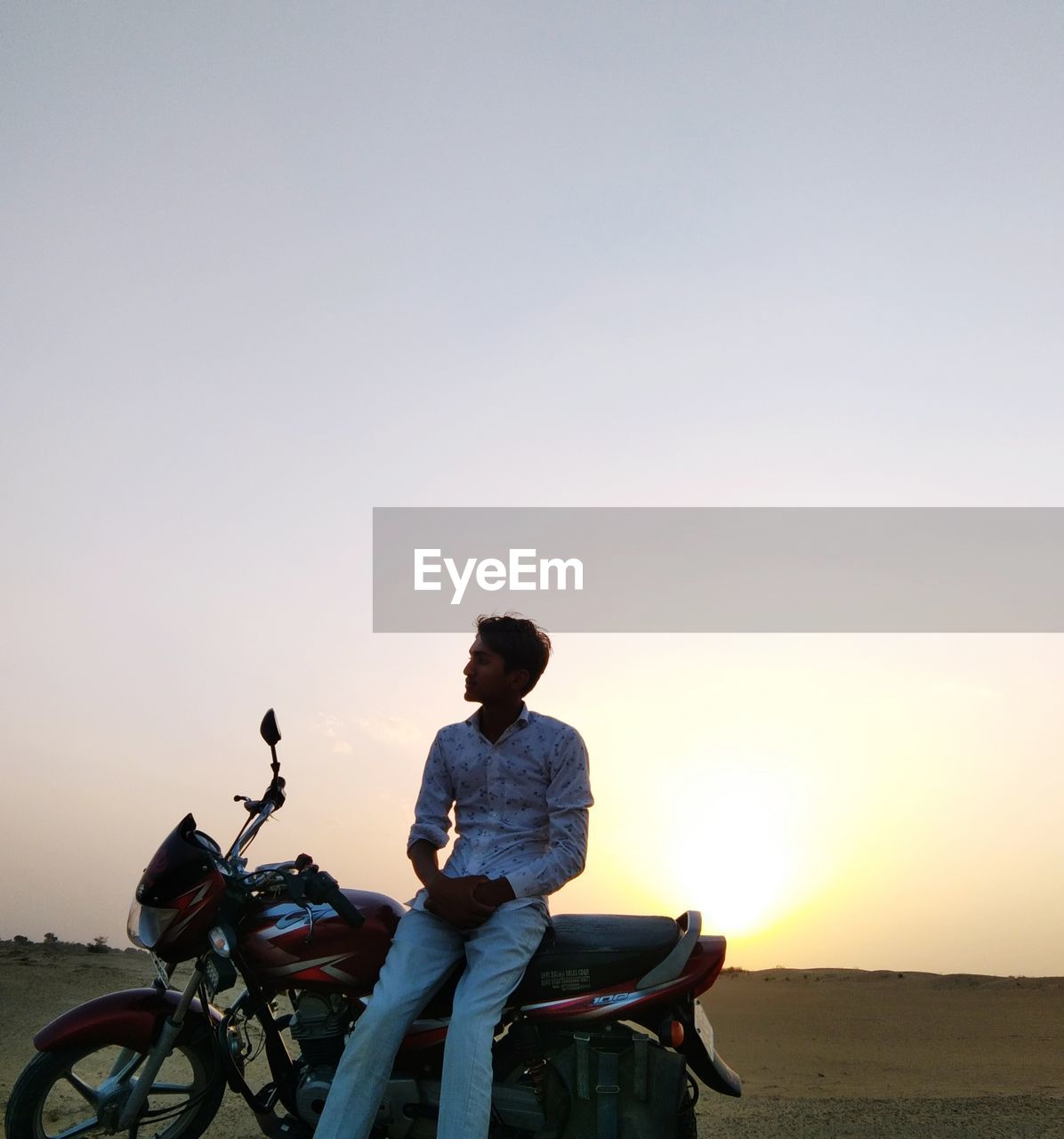 Man riding bicycle on road against sky during sunset