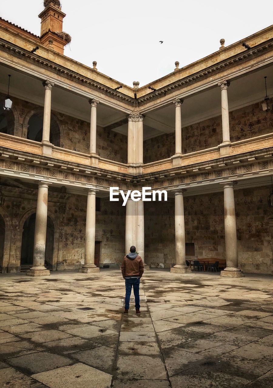 FULL LENGTH REAR VIEW OF MAN STANDING AT HISTORICAL BUILDING