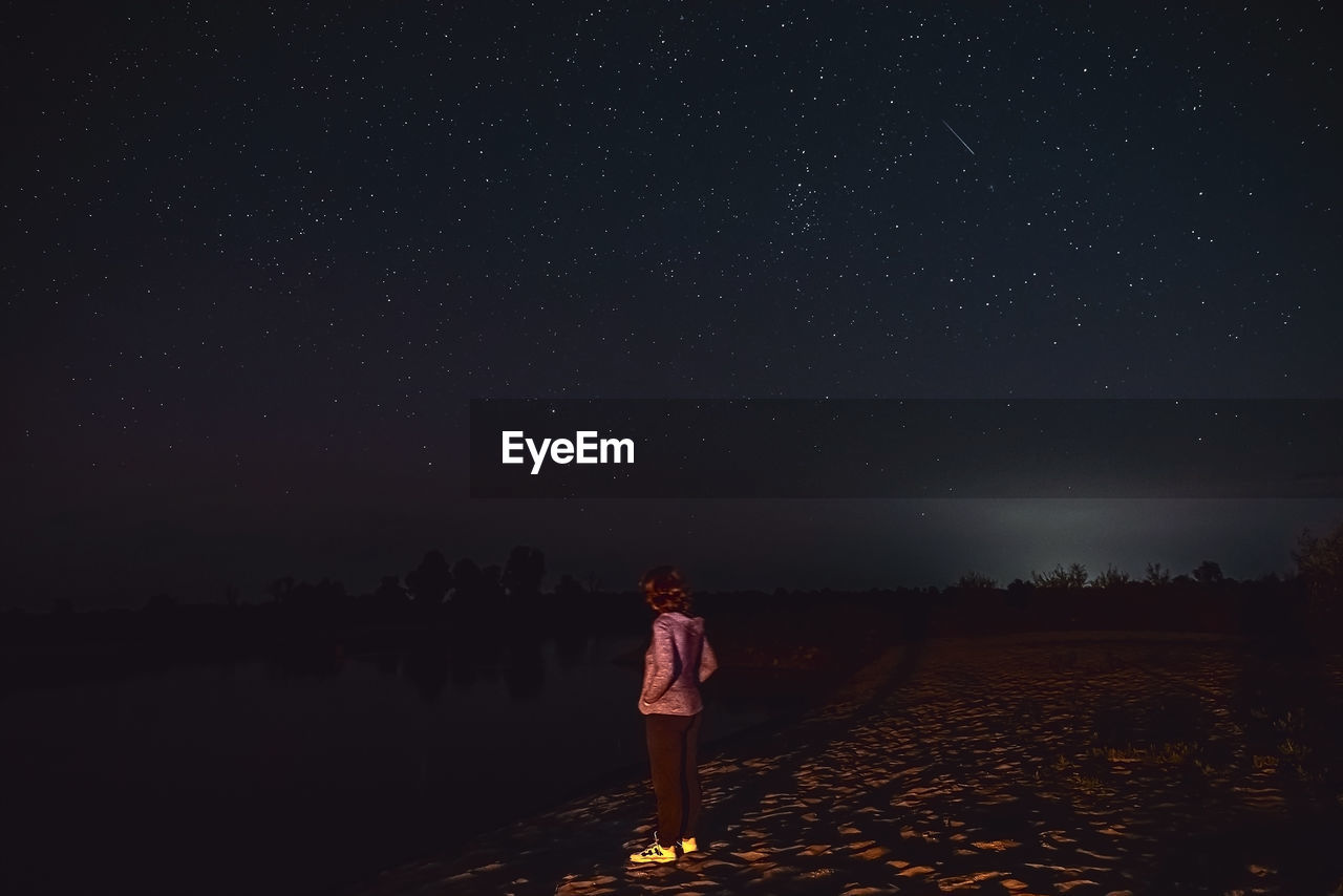 rear view of woman standing on field at night