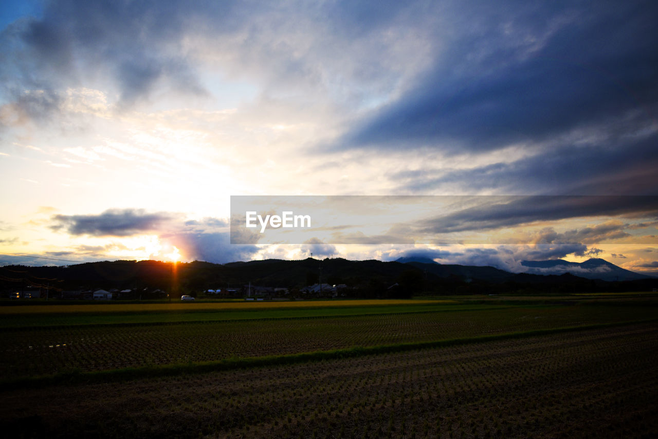 SCENIC VIEW OF FARM AGAINST SKY DURING SUNSET