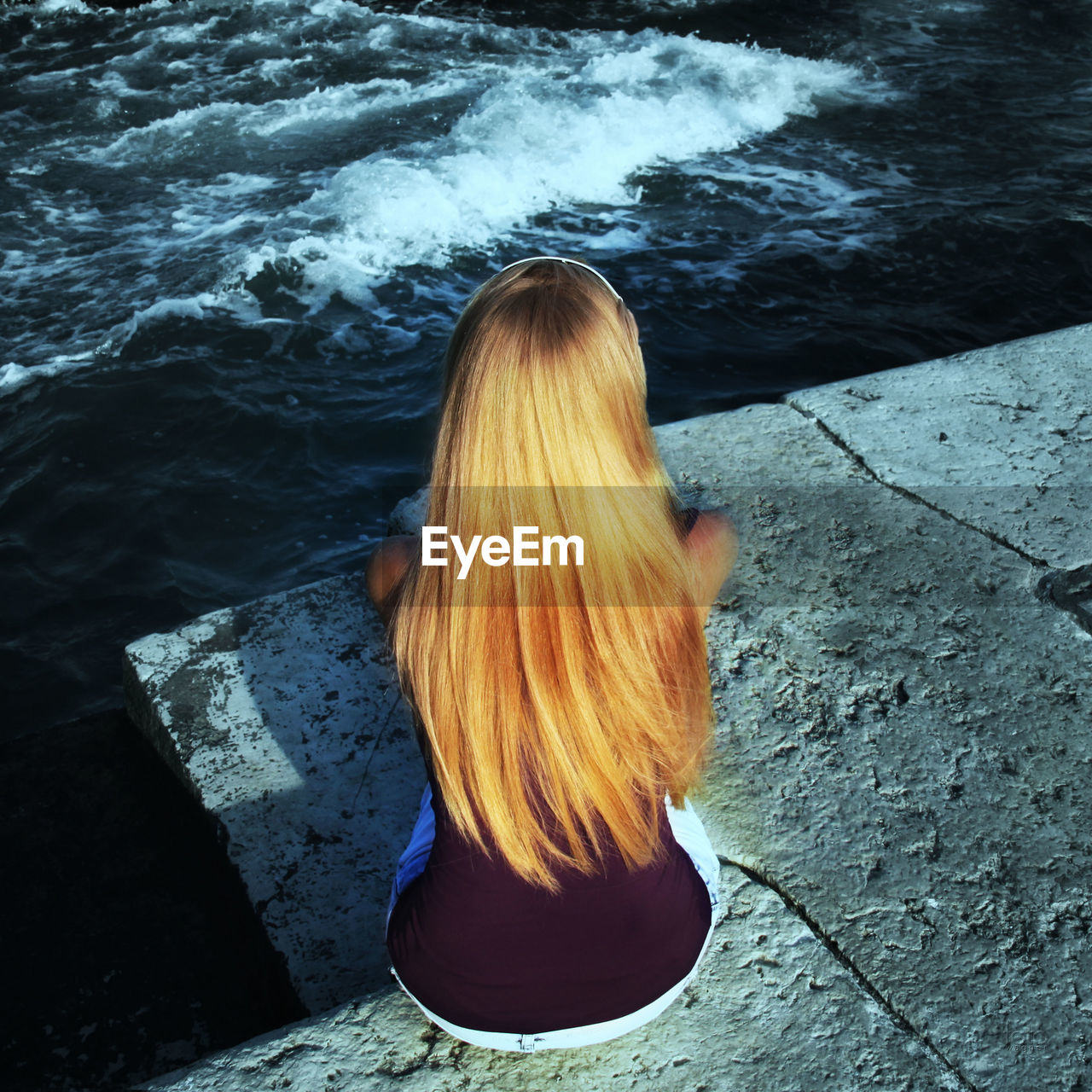 High angle view of young woman sitting at seashore