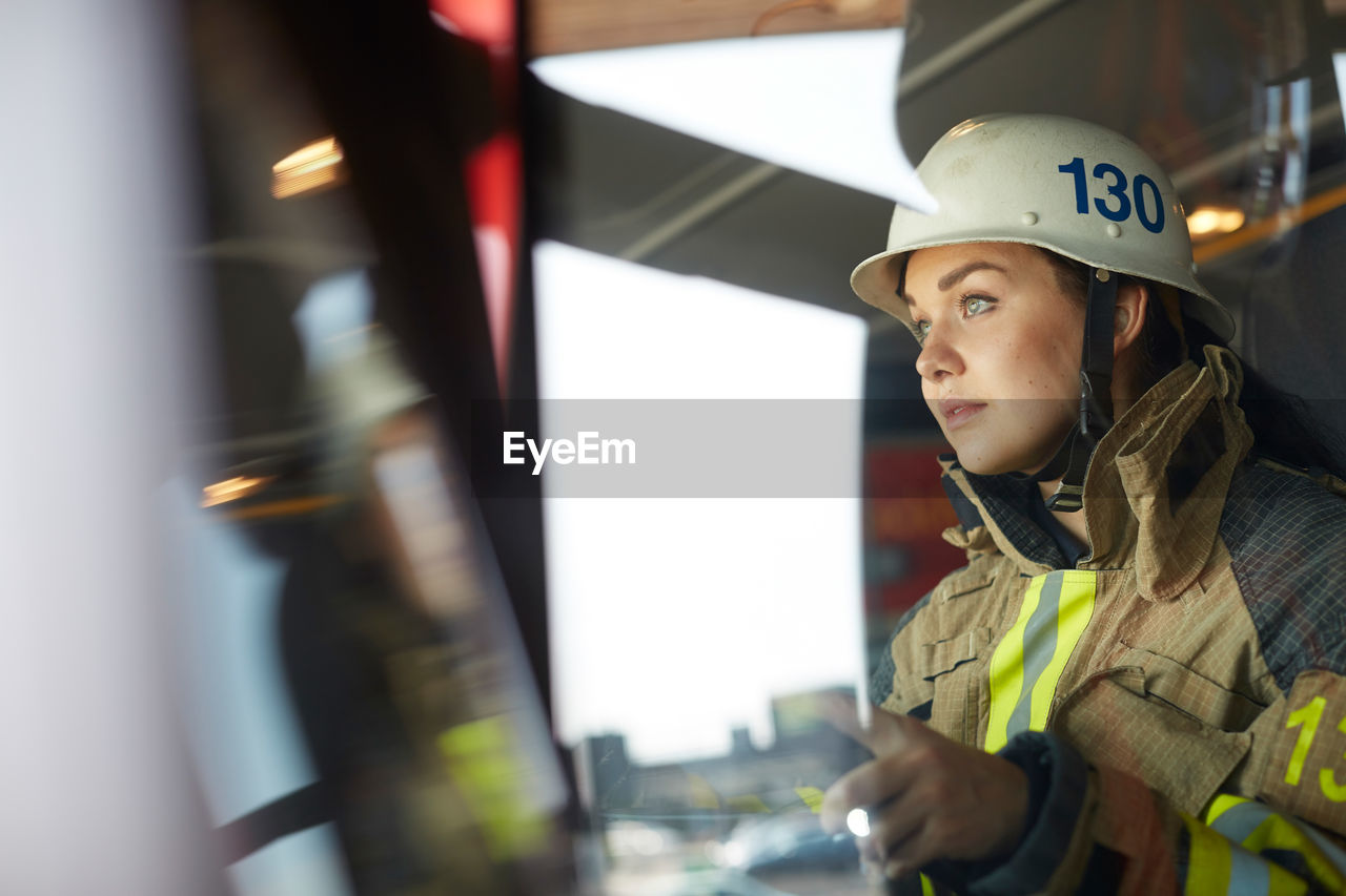 Confident female firefighter sitting in fire engine