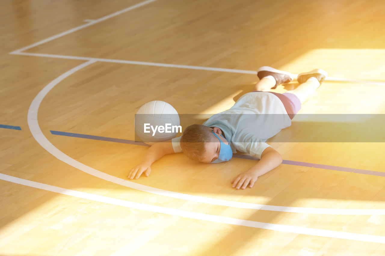 High angle view of boy playing with ball on hardwood floor