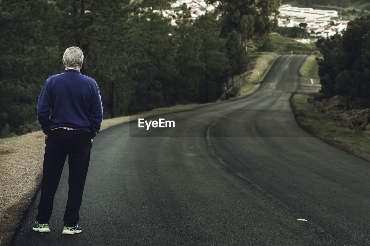 Rear view of man standing on road 