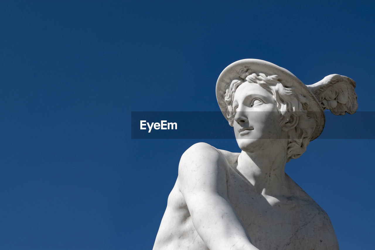 LOW ANGLE VIEW OF STATUES AGAINST BLUE SKY