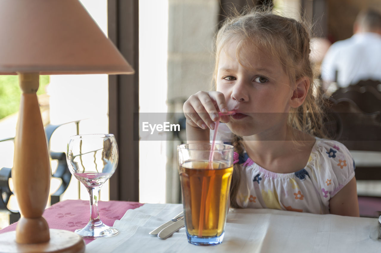 Portrait of girl having drink at table