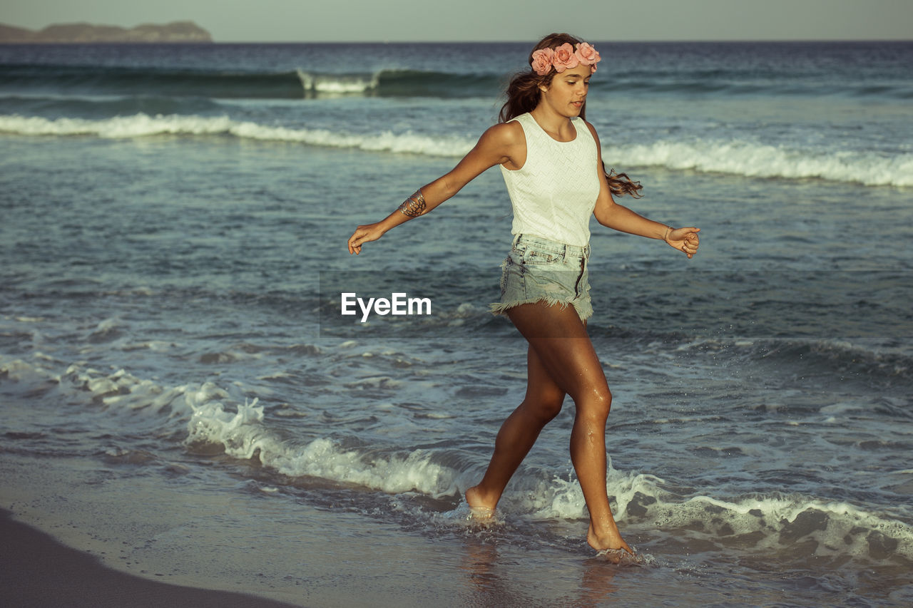 YOUNG WOMAN STANDING ON BEACH