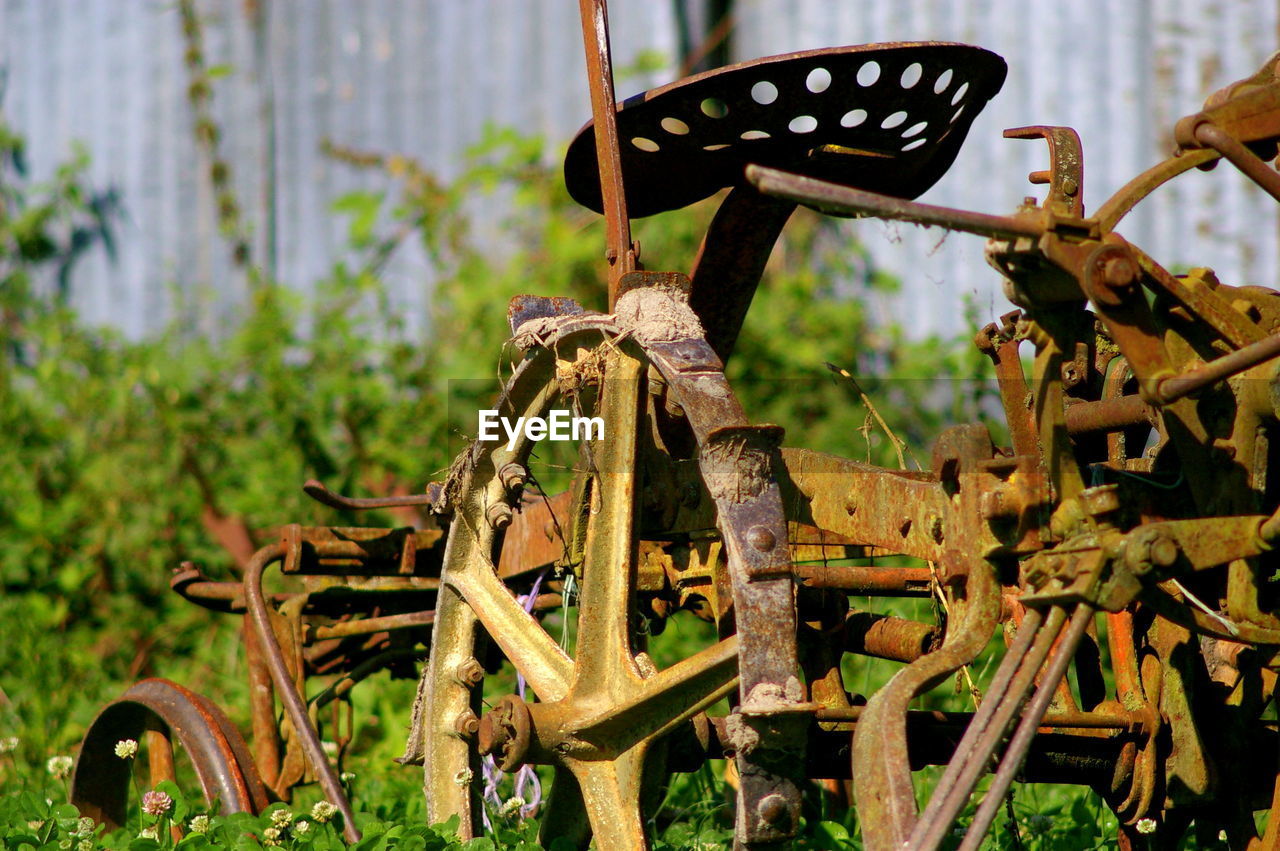 CLOSE-UP OF RUSTY METALLIC ABANDONED ON FIELD