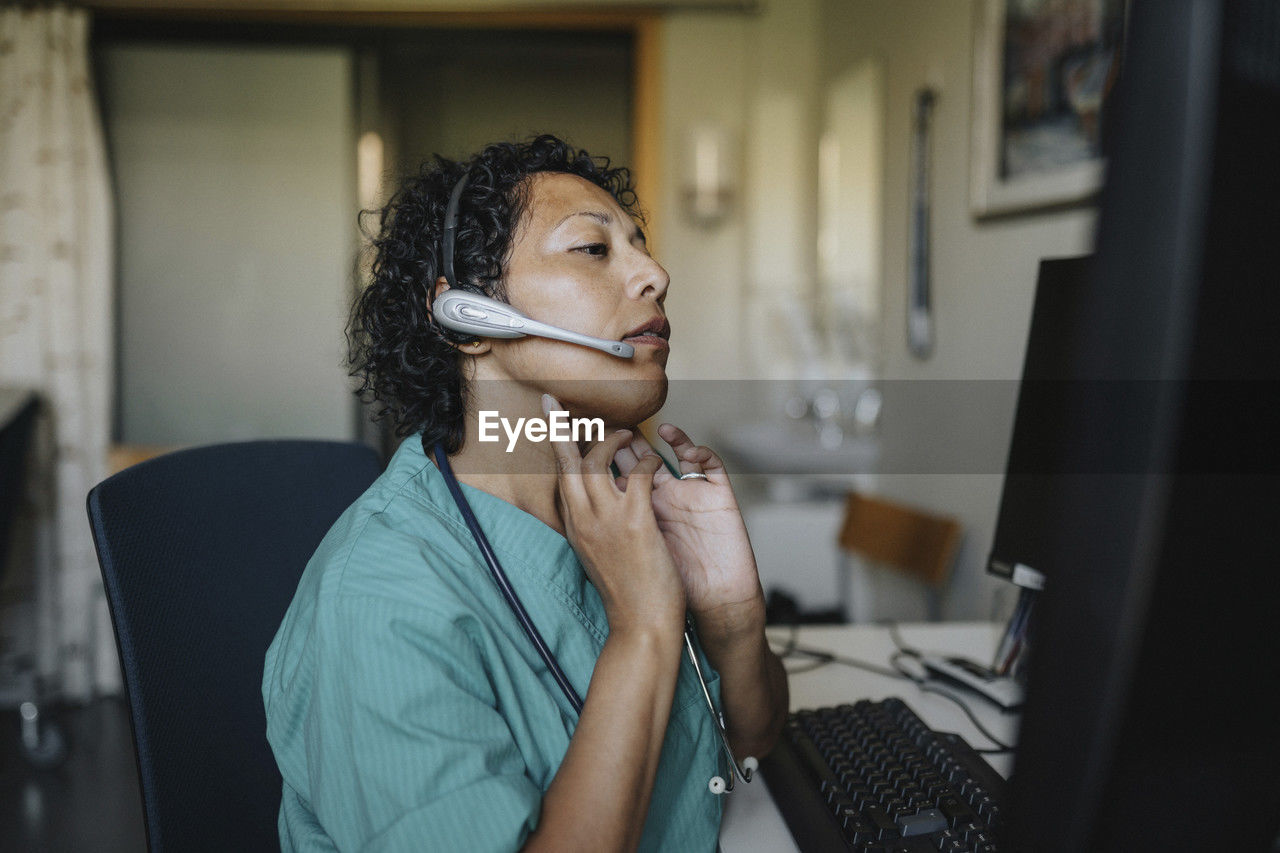 Female doctor giving advice through video call while sitting in hospital