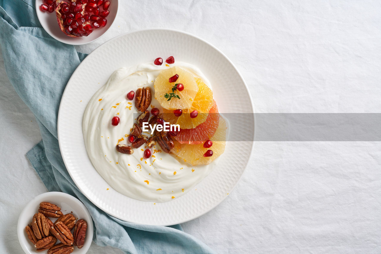 Ricotta with citrus fruits, pecans and honey on white plate on white table. sweet and healthy 