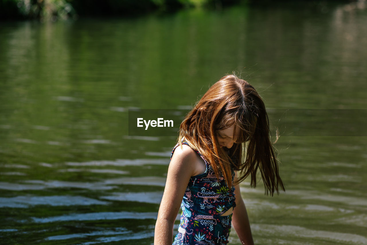 Portrait of young girl standing in a river on a sunny summer day