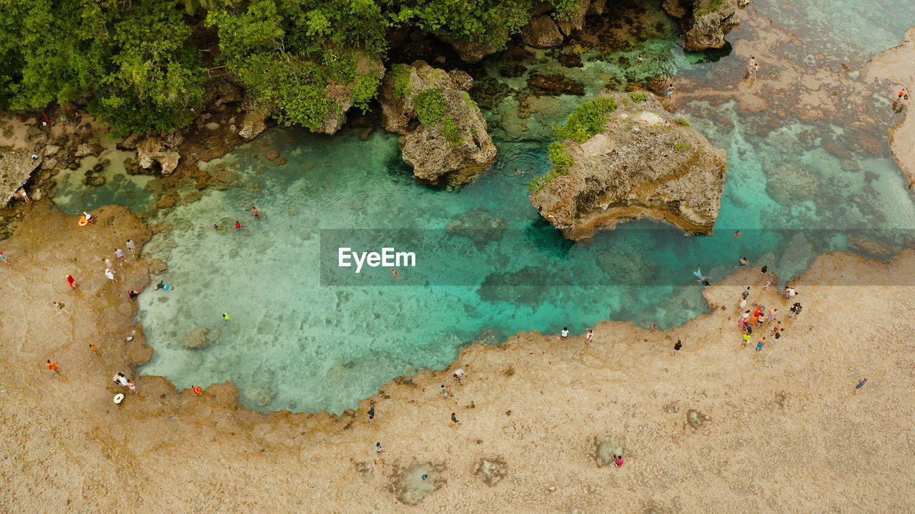 Natural pools on the rocky shore with tourists formed at low tide. magpupungko natural rock pools.