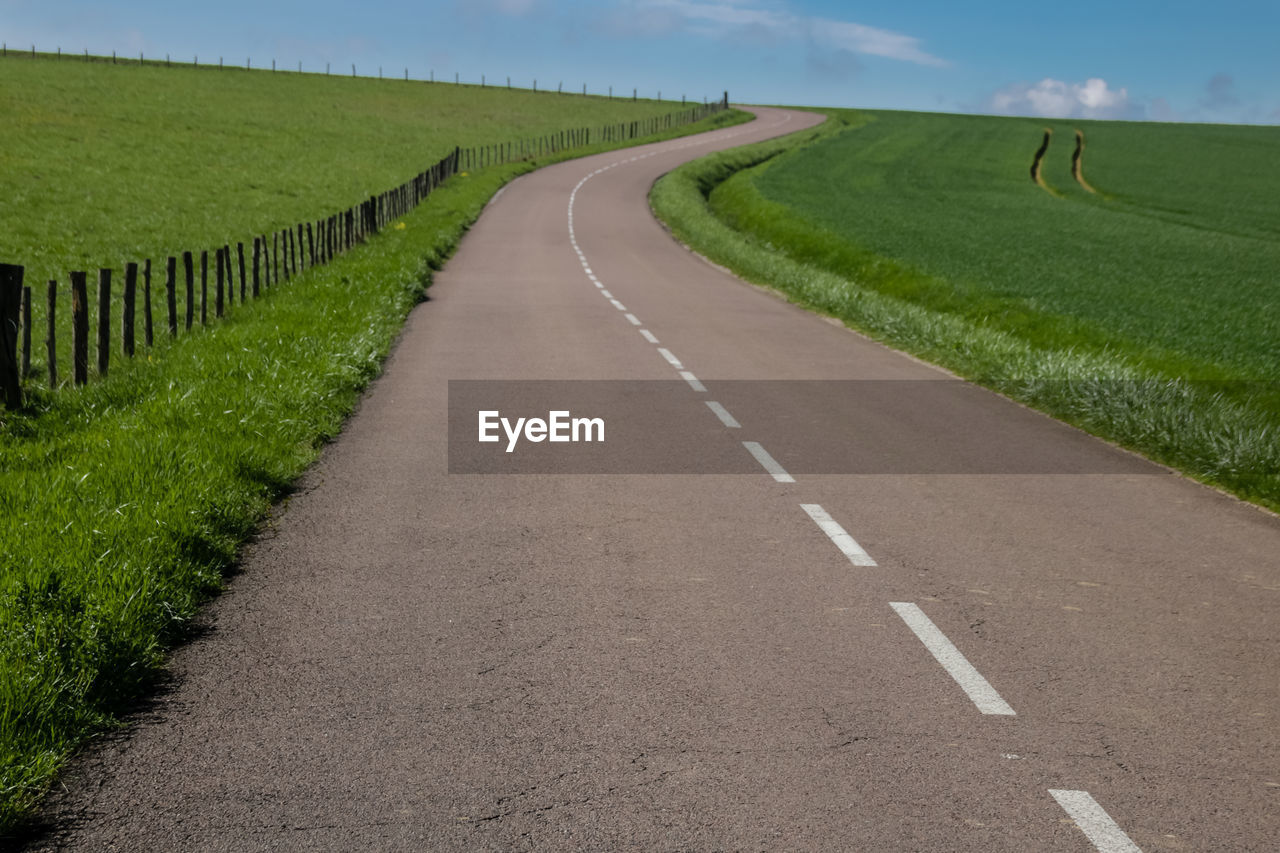 Road amidst field against sky