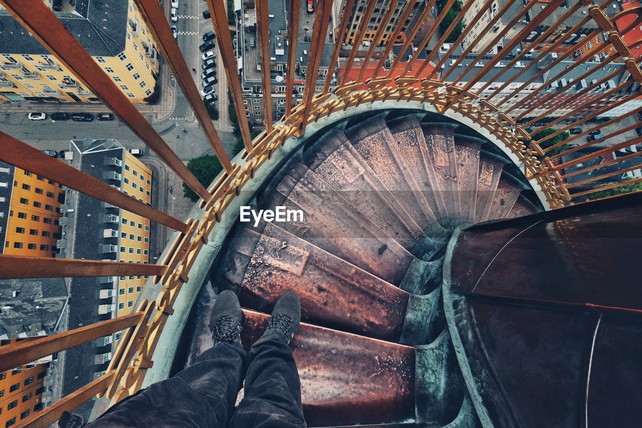 Low section of man standing on spiral staircase in city