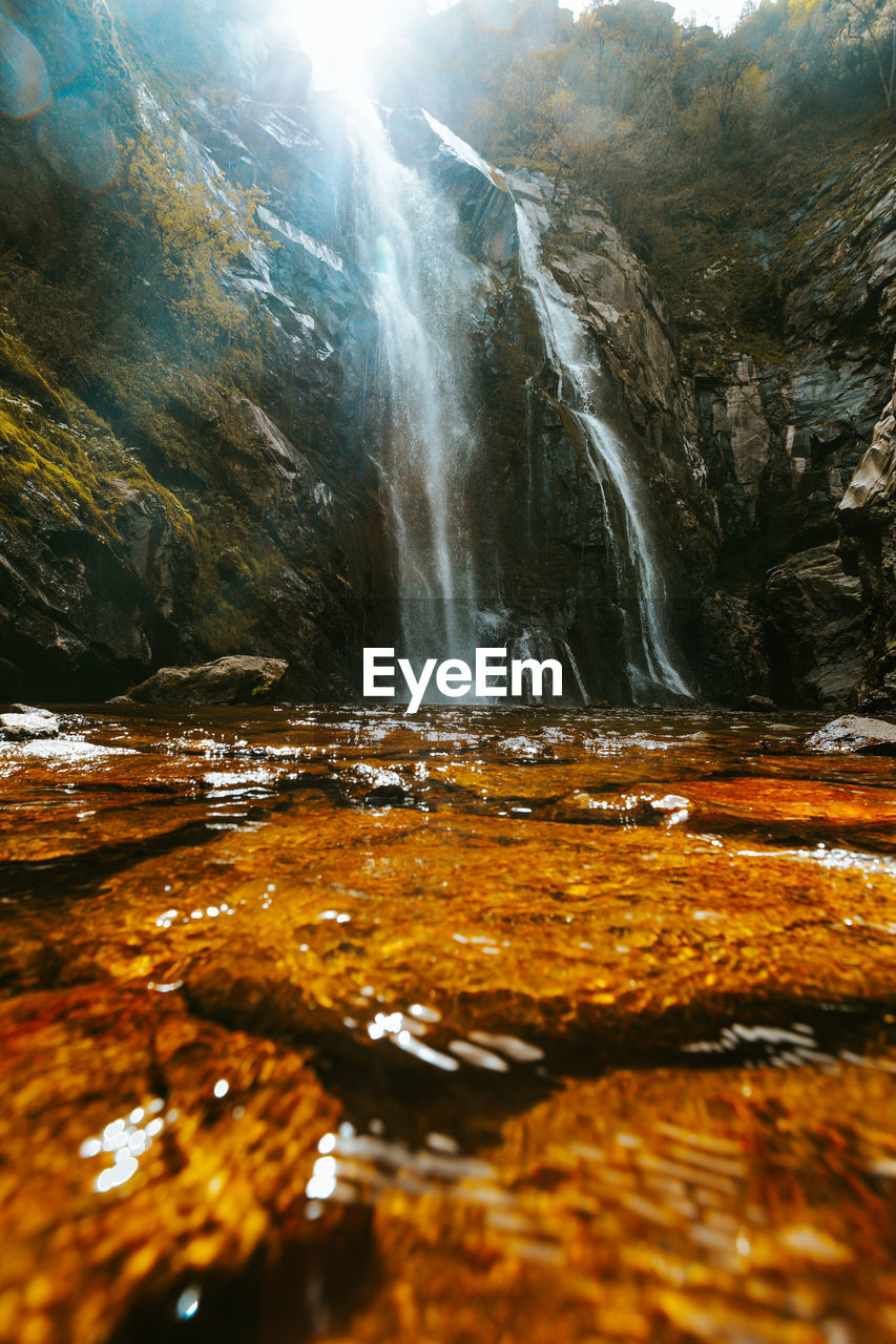 SCENIC VIEW OF WATERFALL AGAINST ROCK