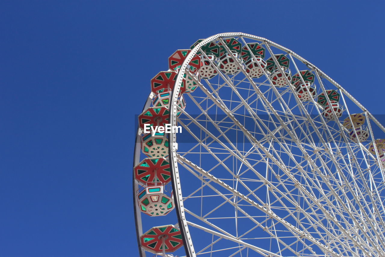 Low angle view of ferris wheel against clear sky on sunny day