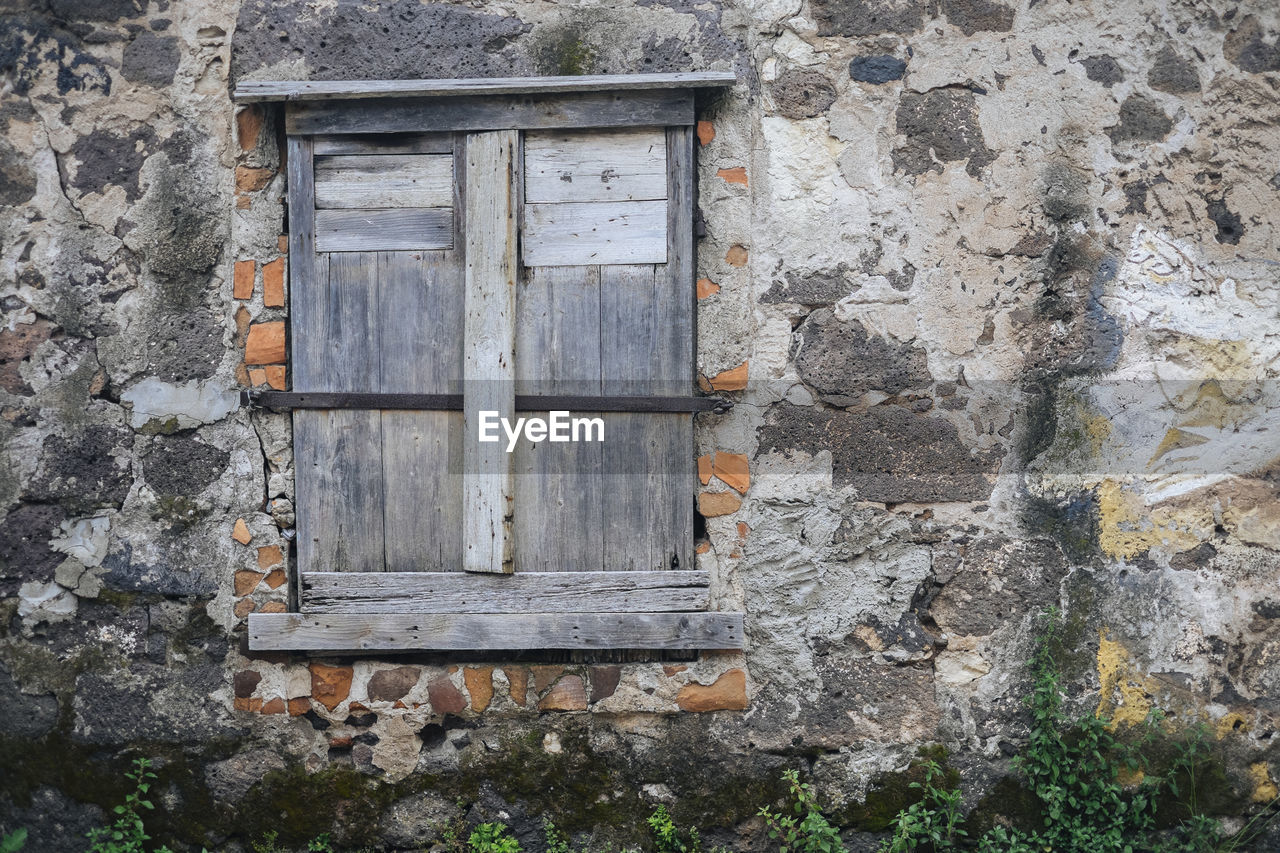 Close-up of closed window amidst old wall