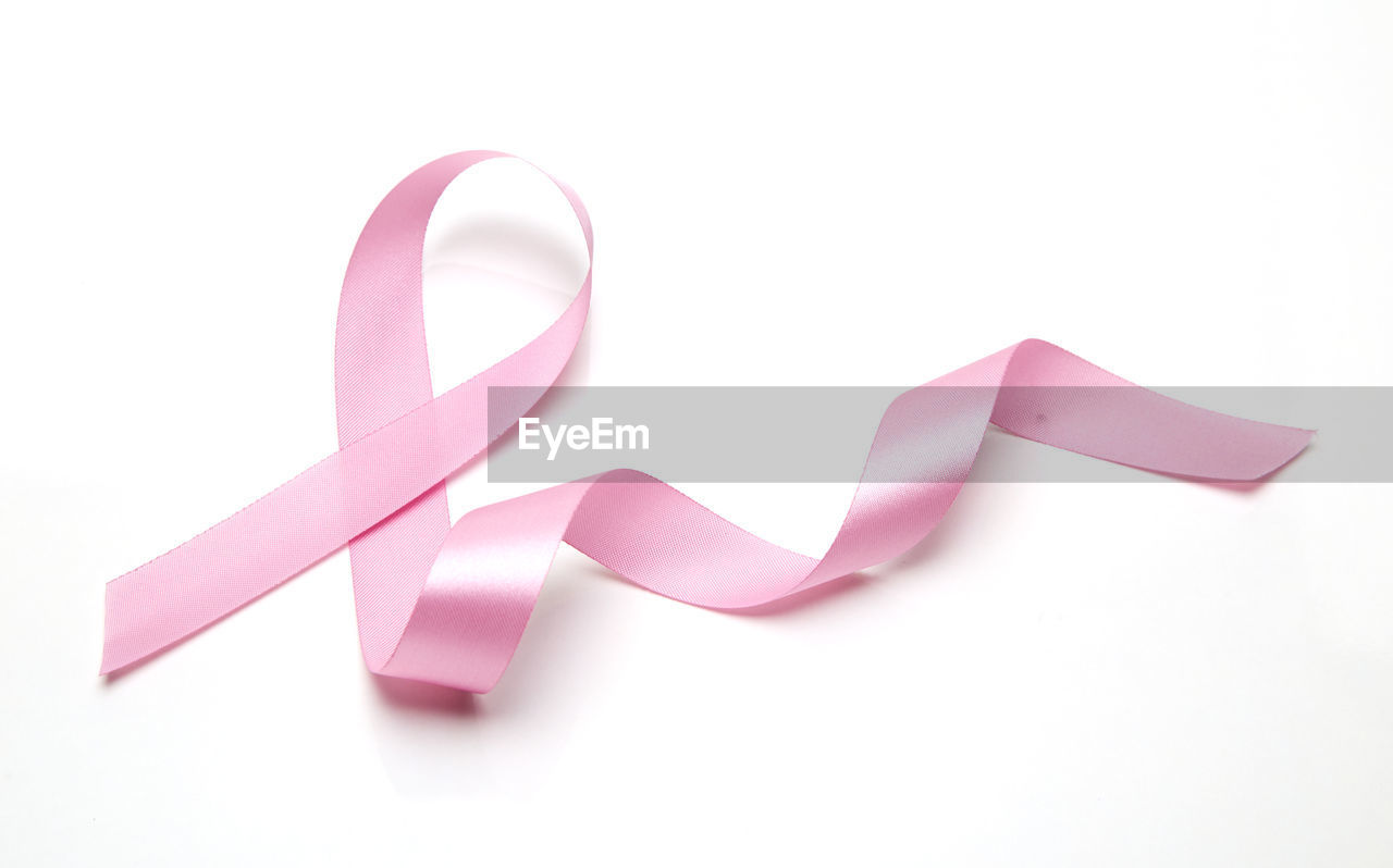 Close-up of breast cancer awareness ribbon over white background