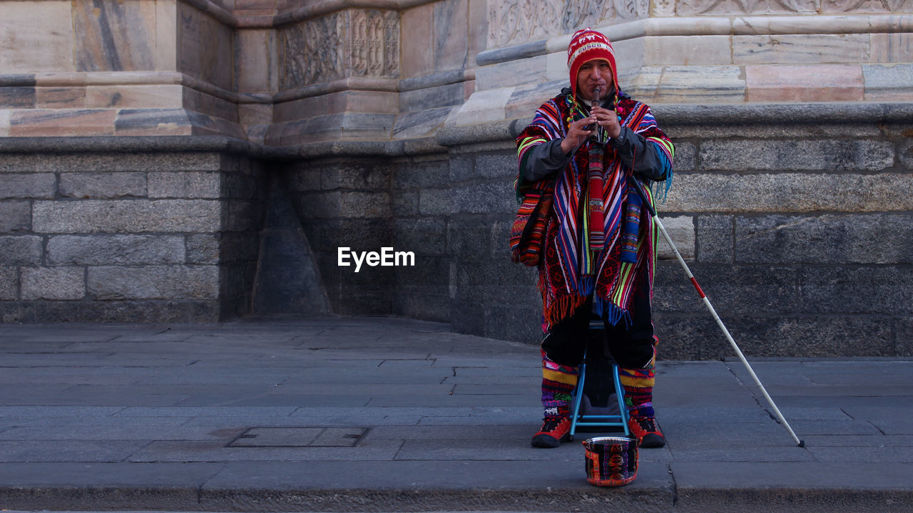 Portrait of street musician playing musical equipment on sidewalk