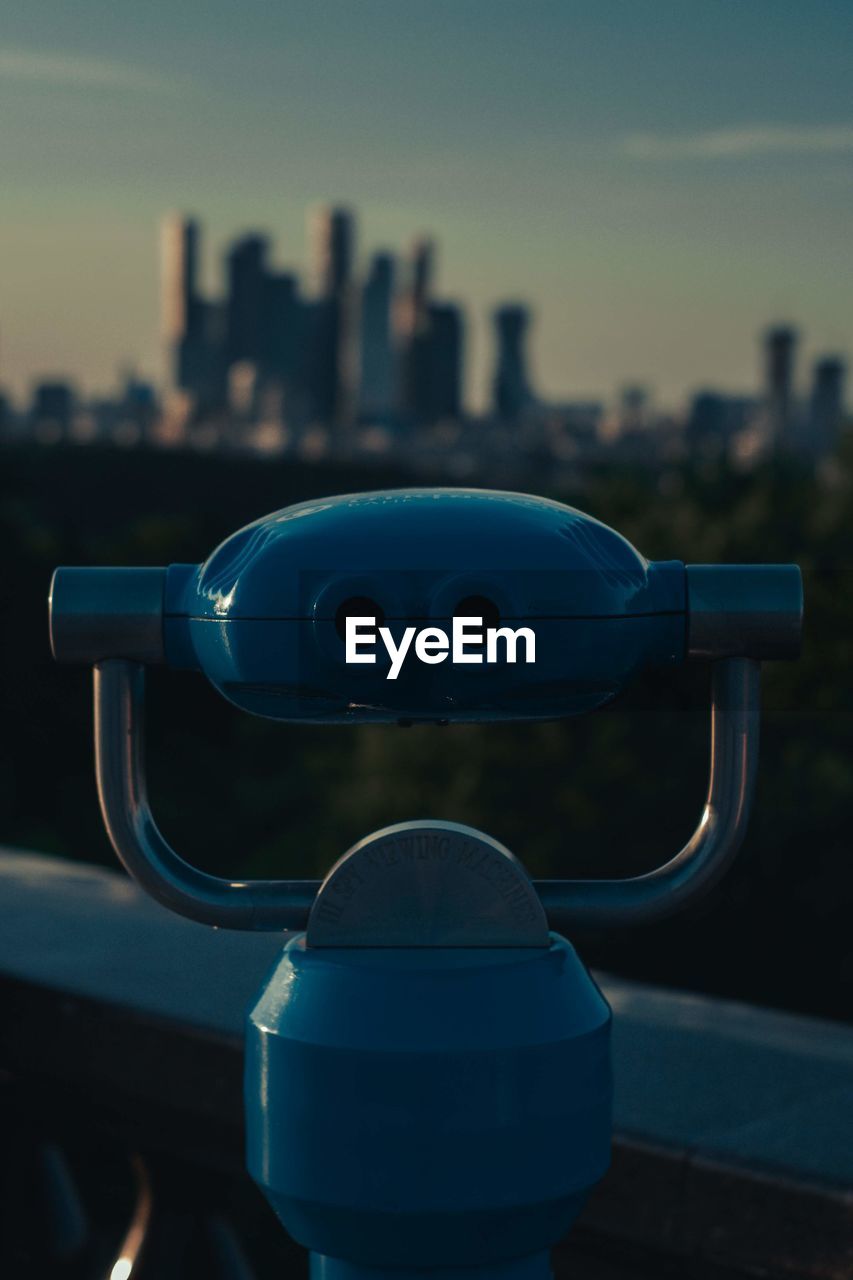 Close-up of coin-operated binoculars against cityscape