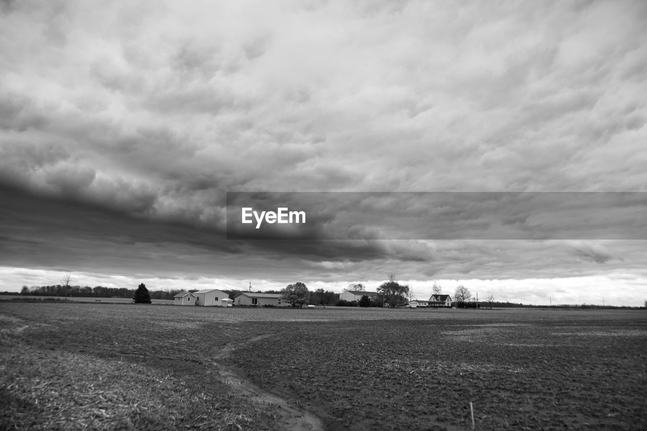 cloud, sky, horizon, environment, landscape, black and white, land, nature, monochrome, monochrome photography, scenics - nature, beauty in nature, field, rural scene, agriculture, no people, storm, cloudscape, dramatic sky, outdoors, plant, tranquility, darkness, day, tranquil scene, overcast, farm, storm cloud, sea, black, water, non-urban scene, grass
