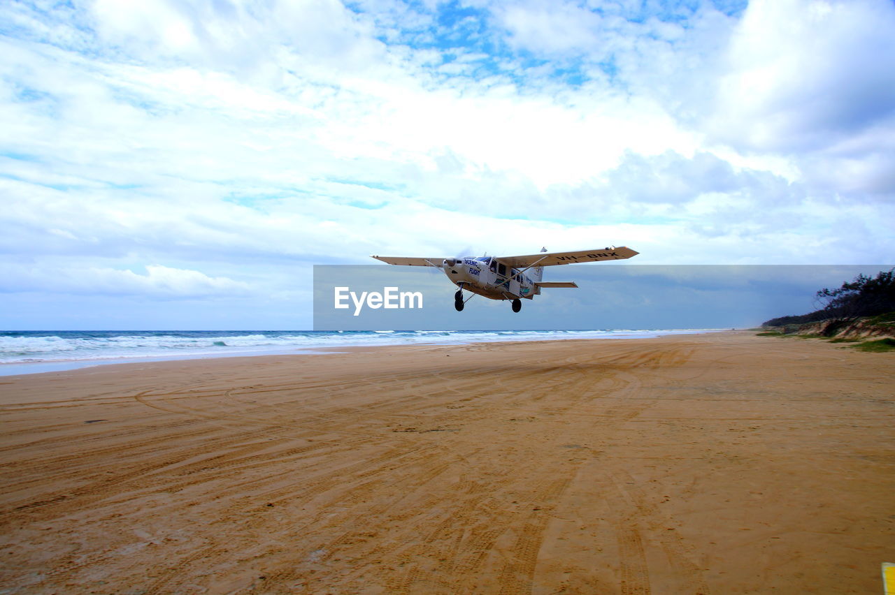 VIEW OF AIRPLANE FLYING OVER BEACH