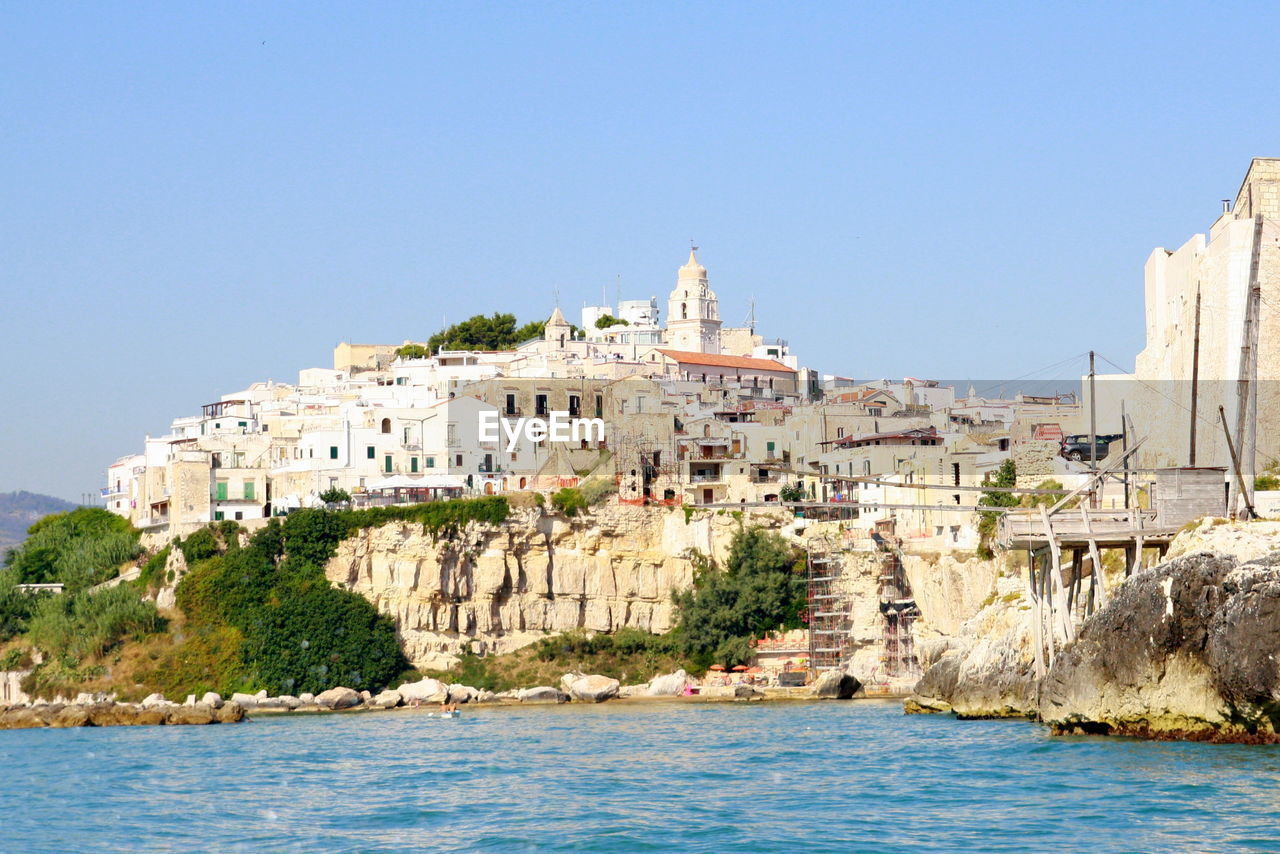 BUILDINGS BY SEA AGAINST BLUE SKY