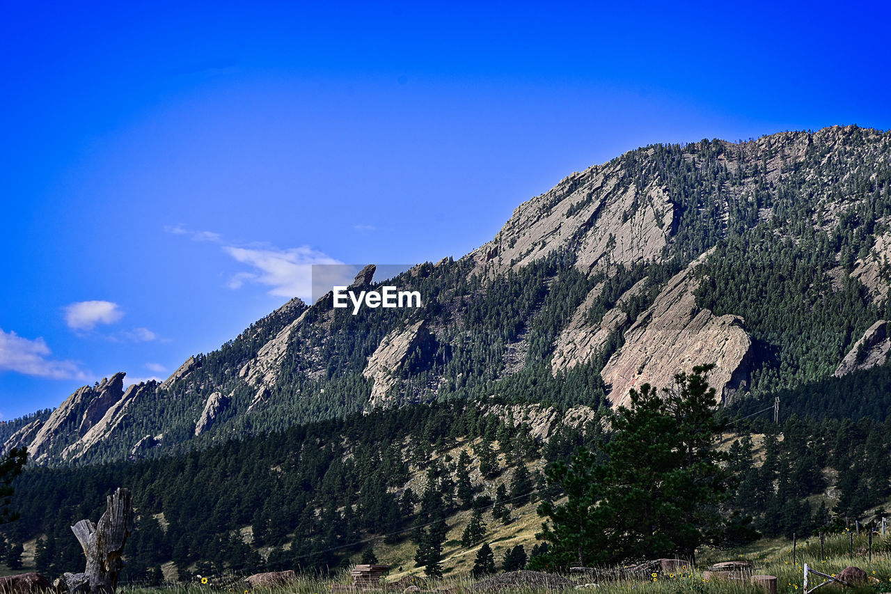 LOW ANGLE VIEW OF SUN SHINING OVER MOUNTAIN