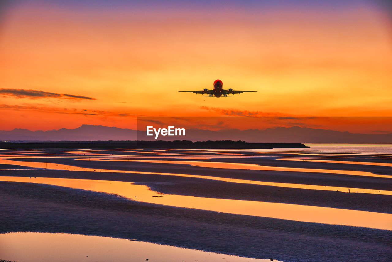 sunset, sky, transportation, horizon, air vehicle, dawn, airplane, nature, mode of transportation, sea, orange color, flying, water, travel, evening, beauty in nature, silhouette, scenics - nature, reflection, cloud, land, motion, beach, ocean, outdoors, environment, dramatic sky, coast, aircraft, travel destinations, no people, afterglow, sun, vehicle, tranquility, tranquil scene, on the move, sunlight, airport