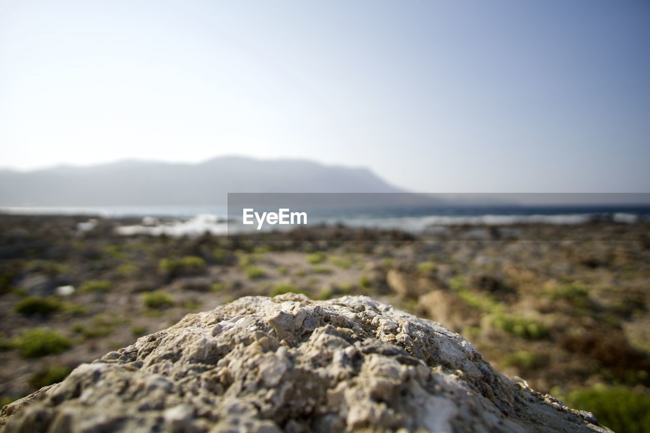 Surface level of rock against landscape and clear sky