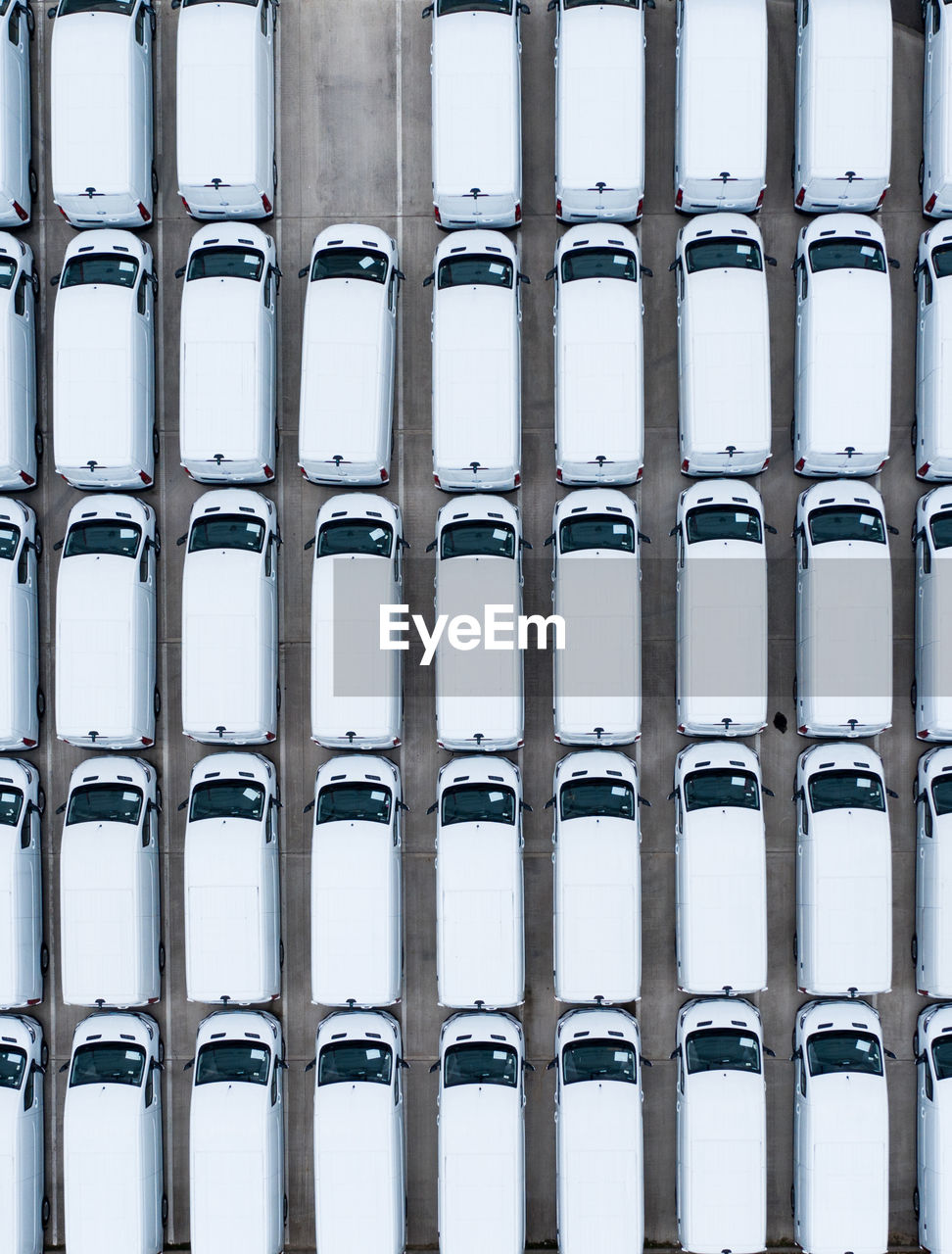 Aerial view of rows of new white vans stockpile on a manufacturers production line