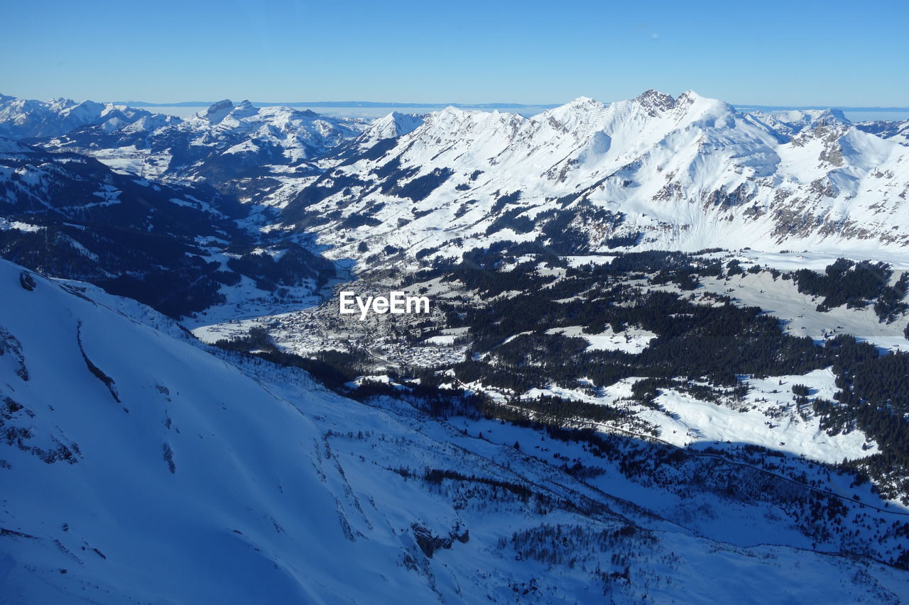 Scenic view of snowcapped mountains against blue sky