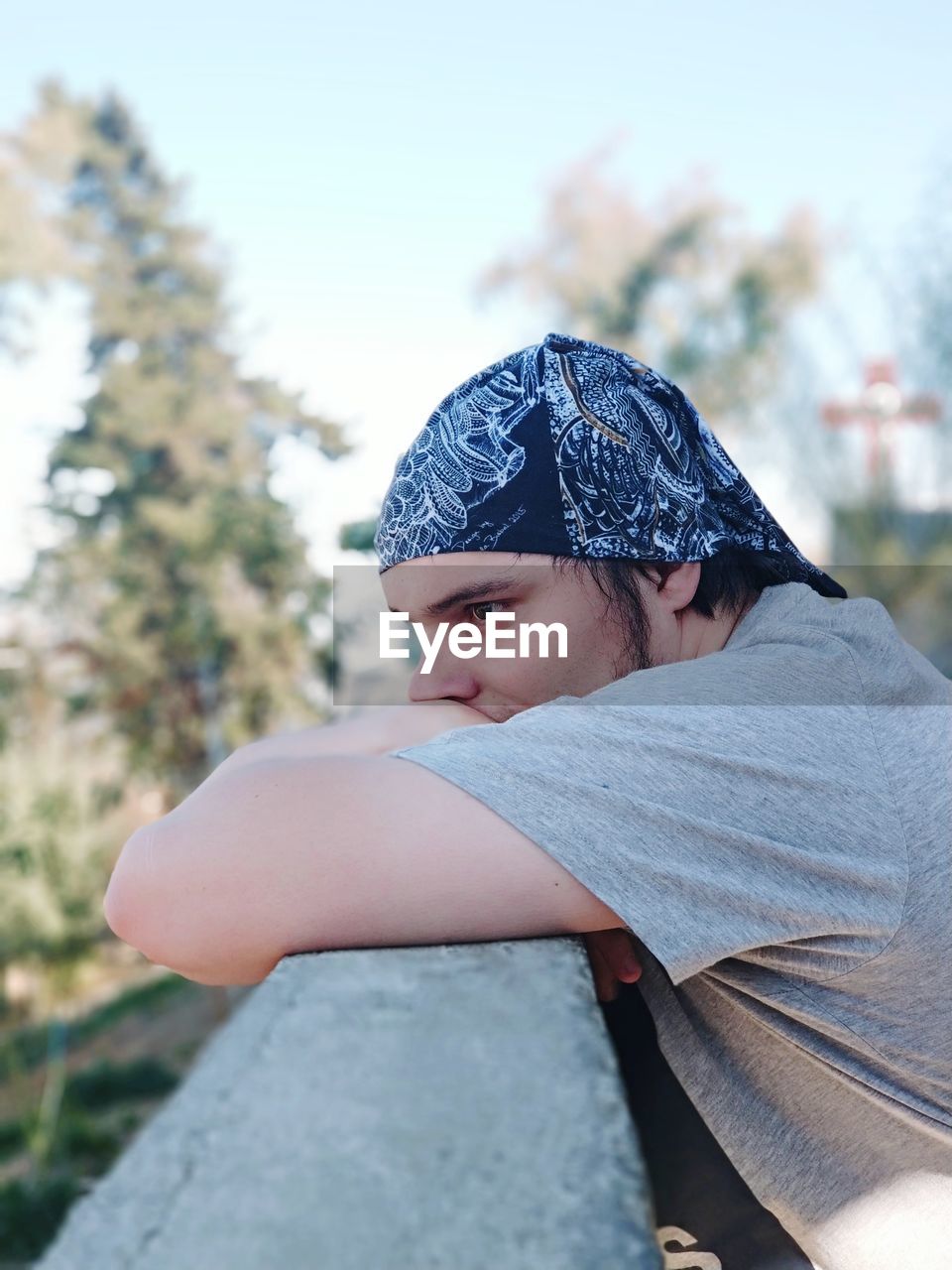 Side view of thoughtful young man by retaining wall