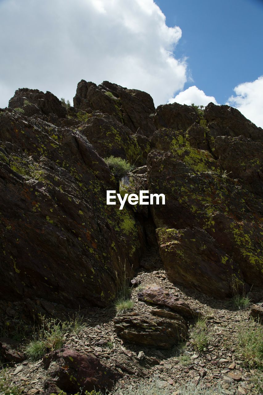 LOW ANGLE VIEW OF ROCK FORMATION AMIDST ROCKS AGAINST SKY