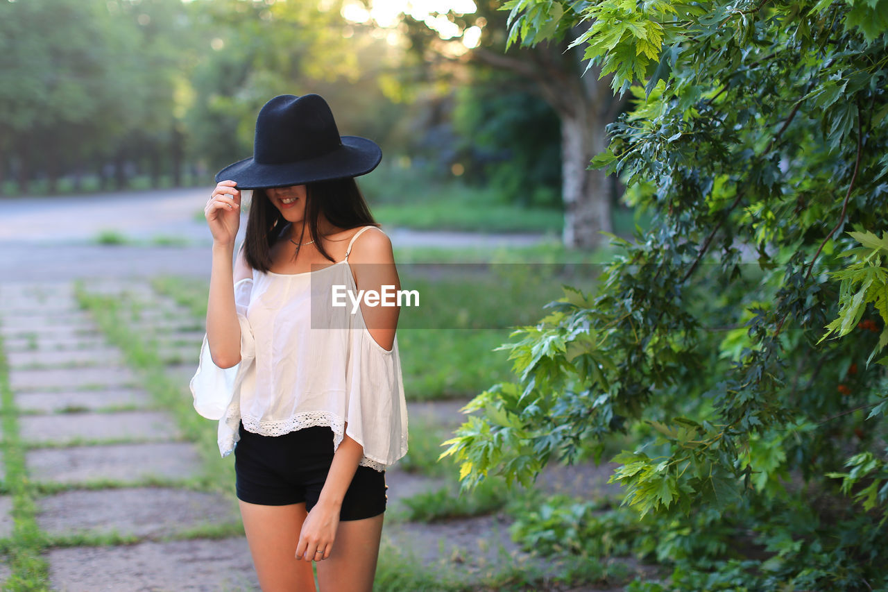 Woman wearing hat standing against plants