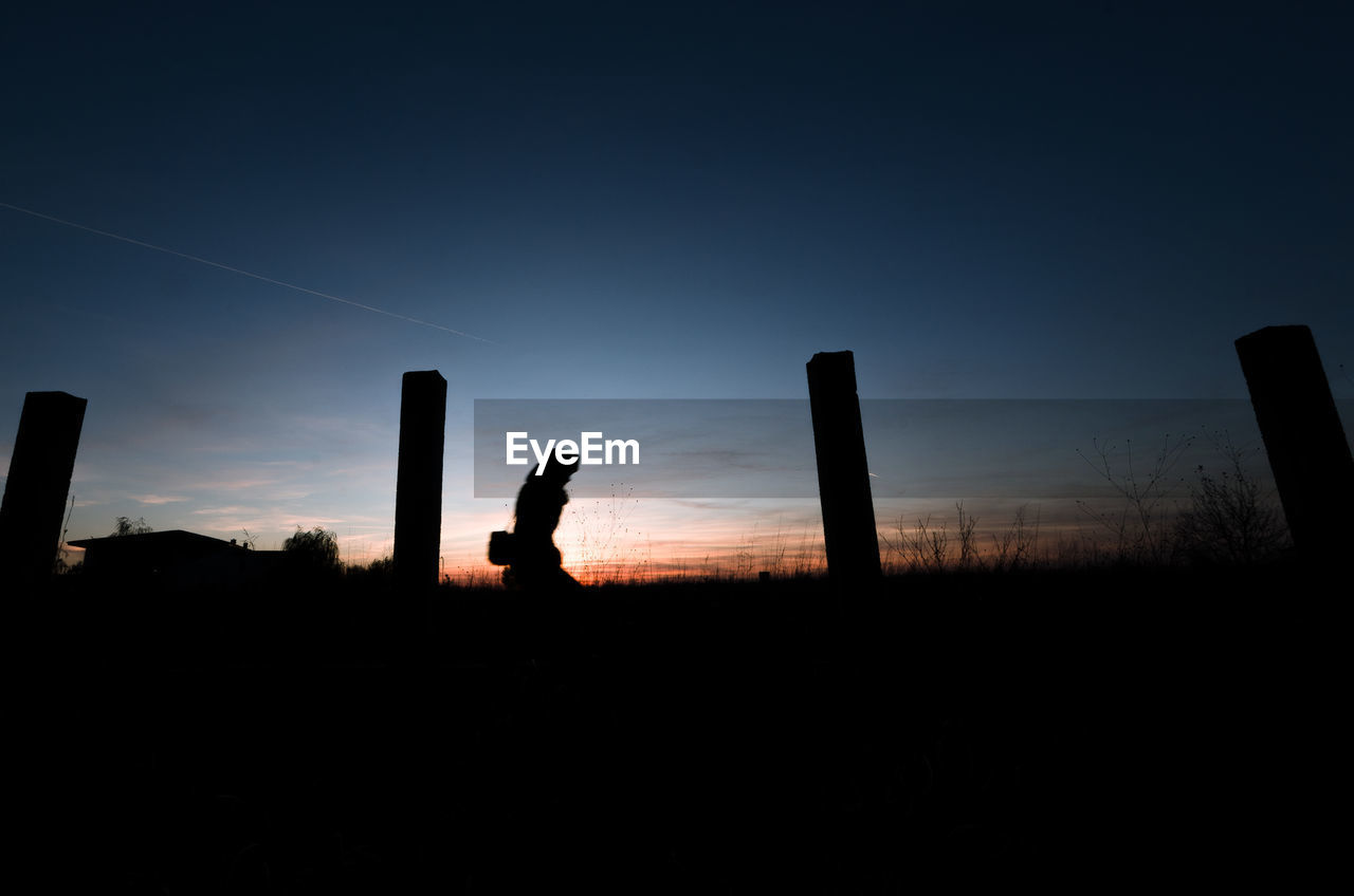 Silhouette person on field against sky during sunset