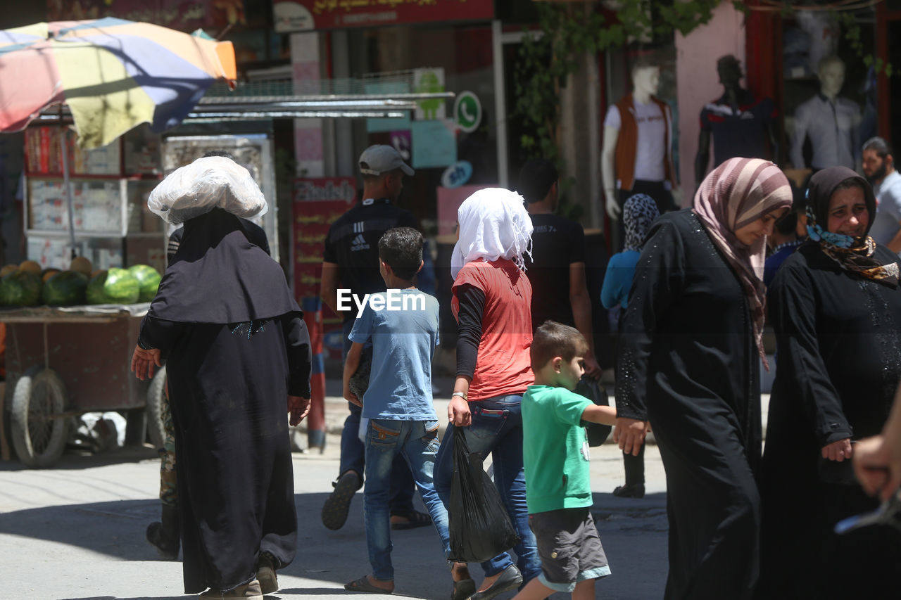 REAR VIEW OF COUPLE WALKING ON STREET